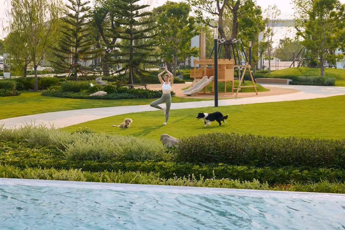 05_buy-house-vs-condo.jpg หญิงสาวทำกิจกรรมกลางแจ้งอย่างโยคะและพาสุนัขเดินเล่นในพื้นที่สีเขียว