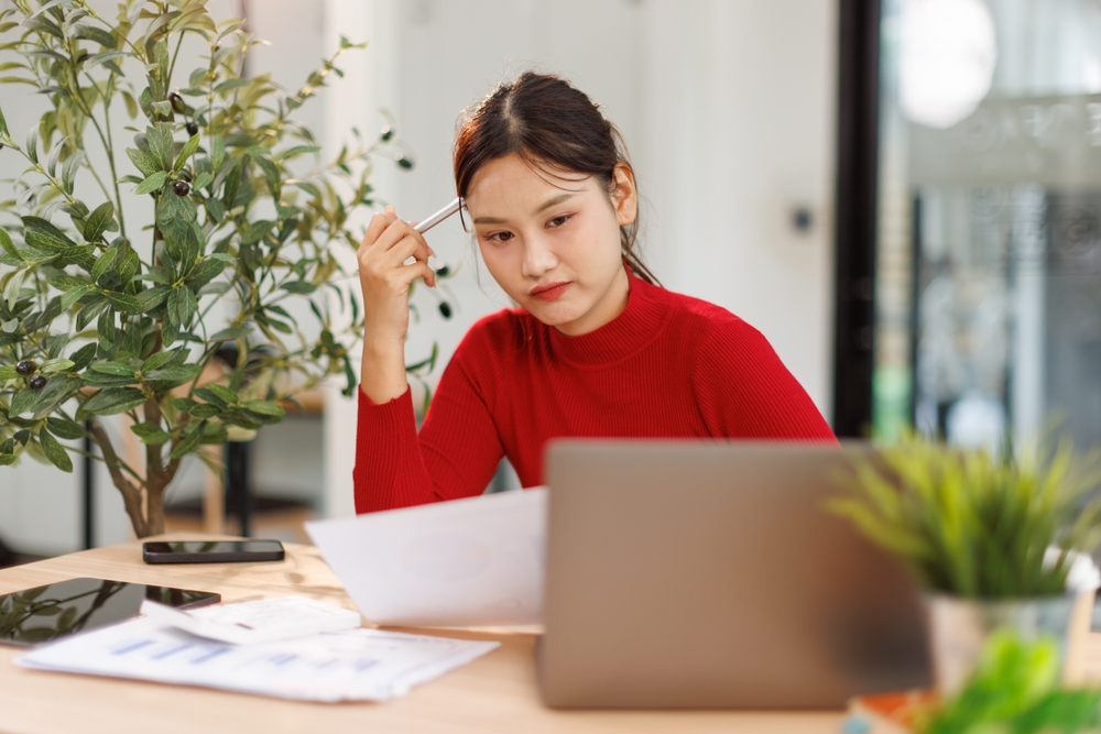 หญิงสาวเจ้าของบ้านกำลังตรวจสอบเอกสารก่อนกู้เงินต่อเติม รีโนเวทบ้าน