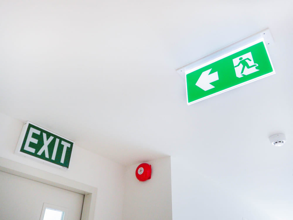10_ap-condo-qc-standards.jpg ป้ายไฟสีเขียวบอกทางออกฉุกเฉิน และกริ่งสัญญาณเตือนภัยสีแดงที่ติดตั้งบริเวณทางเดินและบันไดหนีไฟ