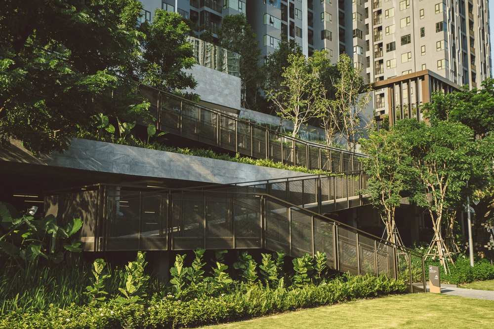 12_ap-condo-qc-standards.jpg การจัดภูมิทัศน์และทางเดินยกระดับท่ามกลางต้นไม้ใหญ่รอบโครงการคอนโด AP