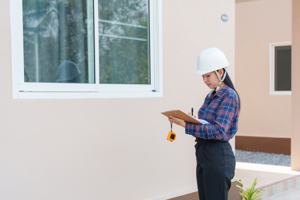 07_what-is-building-setback-regulations.jpg หญิงสาวตรวจระยะร่นอาคารของบ้านที่เพึ่งก่อสร้างเสร็จ